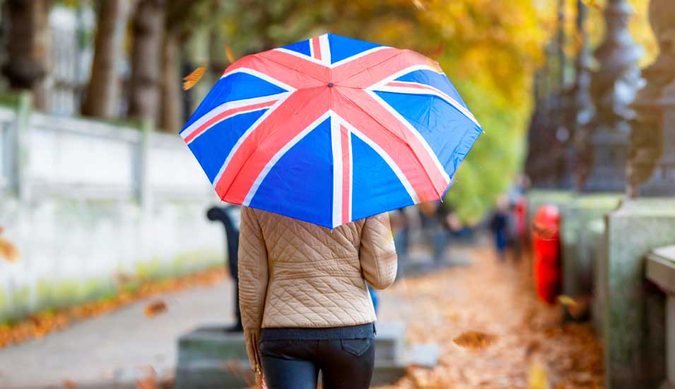 Eine Frau unter einem Schirm im Union-Jack-Muster von hinten.
