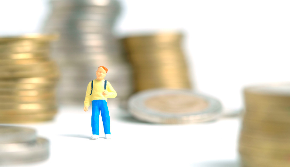 Spielfigur eines Menschen vor Stapeln Kleingeld.