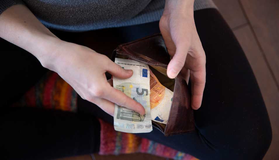 Symbolbild für Armut und Geldmangel: Junger Mensch zählt kleine Euronoten in Geldbeutel