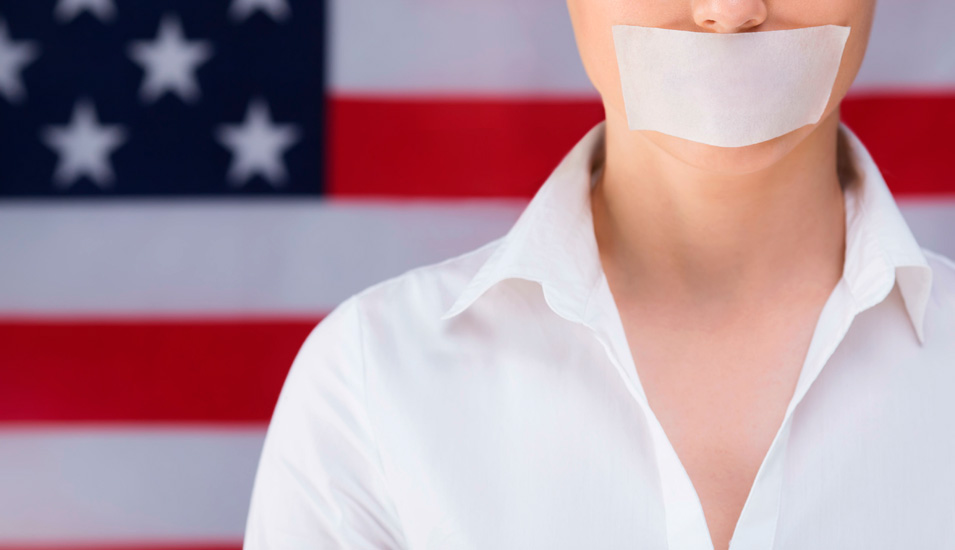 Symbolbild Redefreiheit USA: Frau mit zugeklebtem Mund vor US-Fahne.