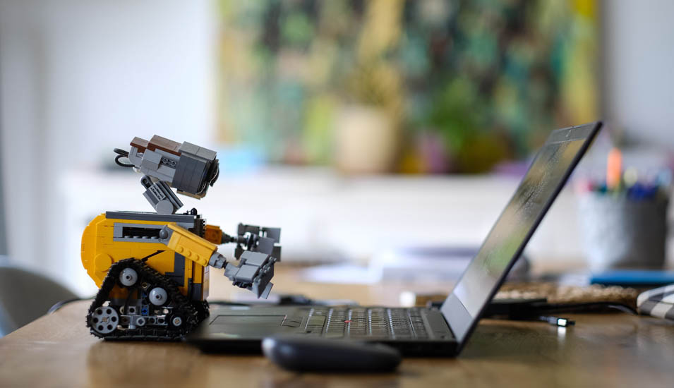 Ein kleiner gelber Roboter beugt sich über einen Laptop