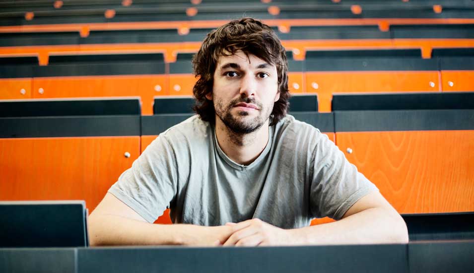 Ein Student sitzt in einem leeren Hörsaal einer Universität