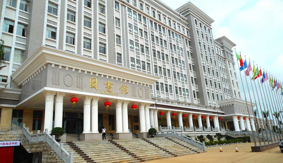 Die chinesische Wirtschaftsuniversität Haikou ist groß, hat viele Fahnen vor dem Gebäude und typisch asiatische Bauelemente.   