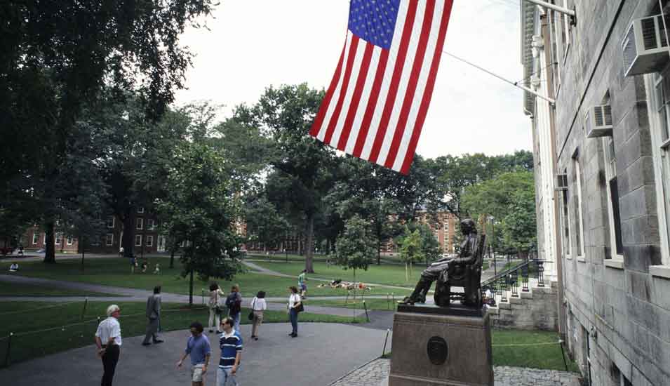 Das Foto zeigt ein Gebäude der Universität Harvard mit einer amerikanischen Flagge.