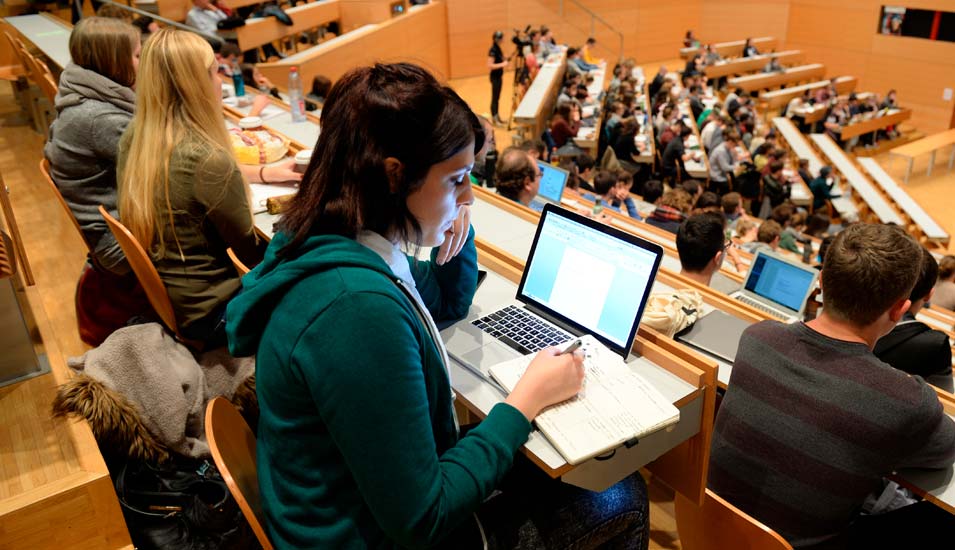 Das Foto zeigt eine Studentin mit Laptop in einem Hörsaal