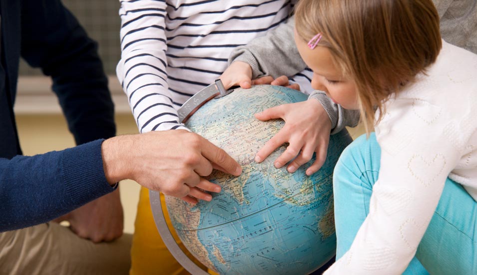 Schüler schauen mit Lehrer auf Globus