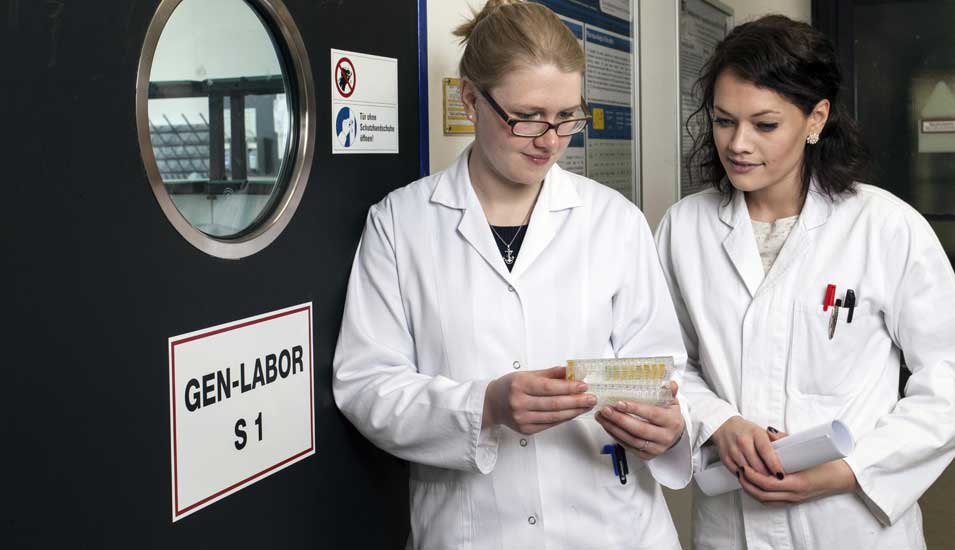 Das Foto zeigt zwei Wissenschaftlerinnen vor einem Genlabor.