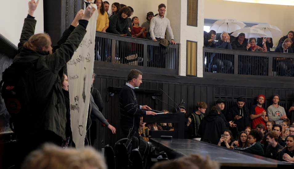 Störer halten ein Plakat hoch im Hörsaal, in dem Bernd Lucker versucht, seine Vorlesung zu halten