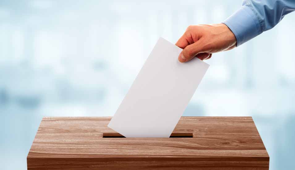 Hand wirft Brief in eine Wahlurne