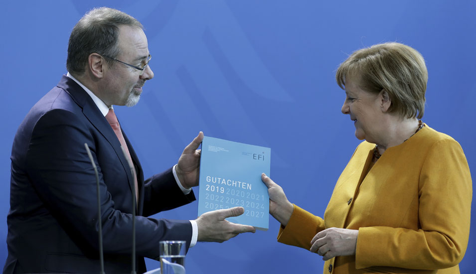 Das Foto zeigt wie Dietmar Harhoff, Mitglied der EFI-Kommission das Jahresgutachten an Bundeskanzlerin Angela Merkel überreicht.
