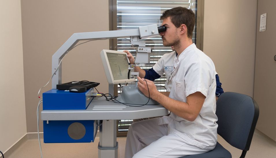 Das Foto zeigt einen Arzt an einem Gerät für die Augenuntersuchung.
