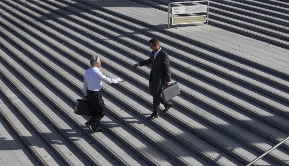 Zwei Männer reichen sich auf breiter Treppe die Hand