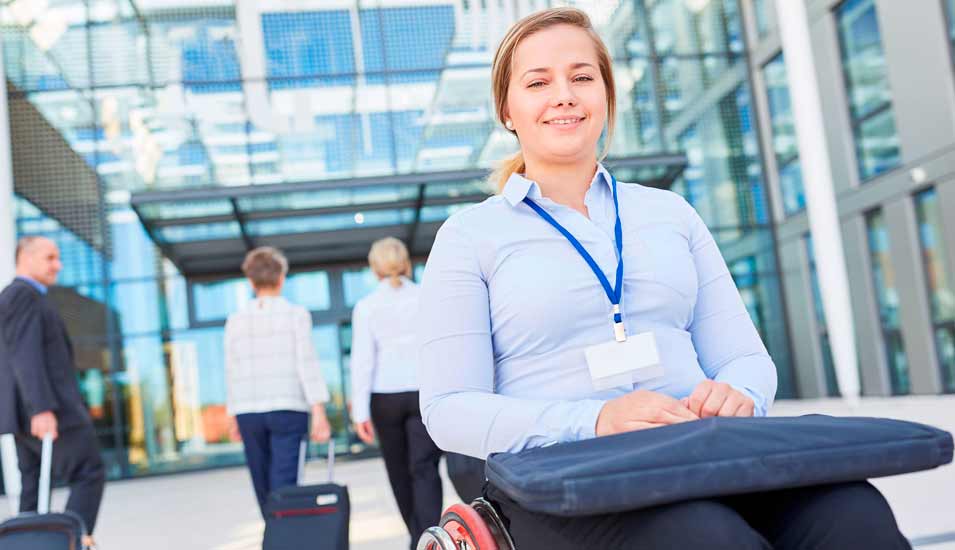 Geschäftsfrau im Rollstuhl mit Laptop-Tasche auf dem Schoß