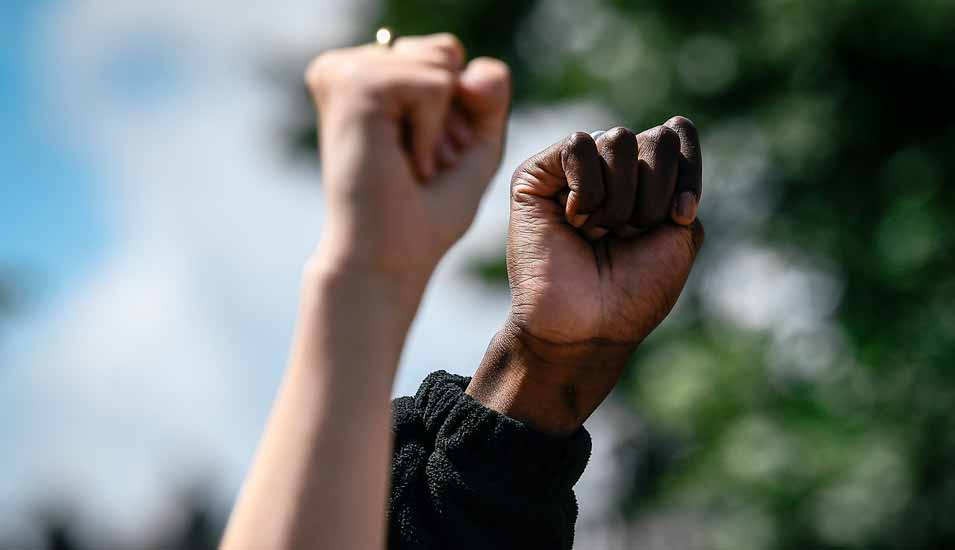 schwarzer und weißer Arm bilden eine Faust als antirassistisches Protestsymbol