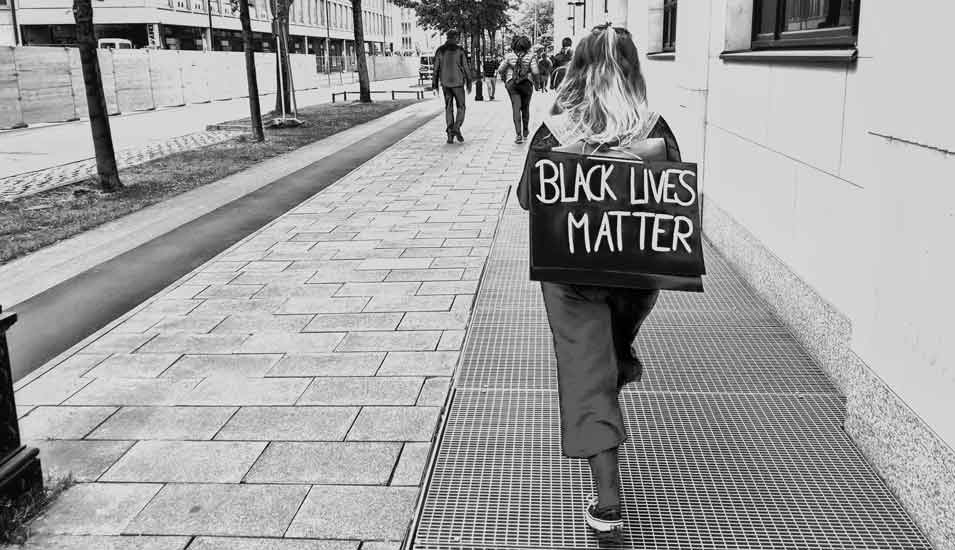 Demonstrantin mit einem "Black Lives Matter"-Schild auf dem Rücken