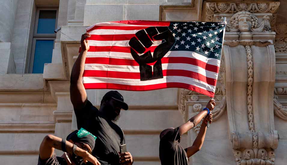 Schwarze Protestanten schwenken eine USA-Flagge mit einem Faussymbol gegen Rassismus