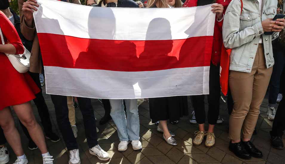 Studierende und Lehrkräfte mit einer Flagge von Belarus bei einer Demonstration an der Minsk State Linguistic University.