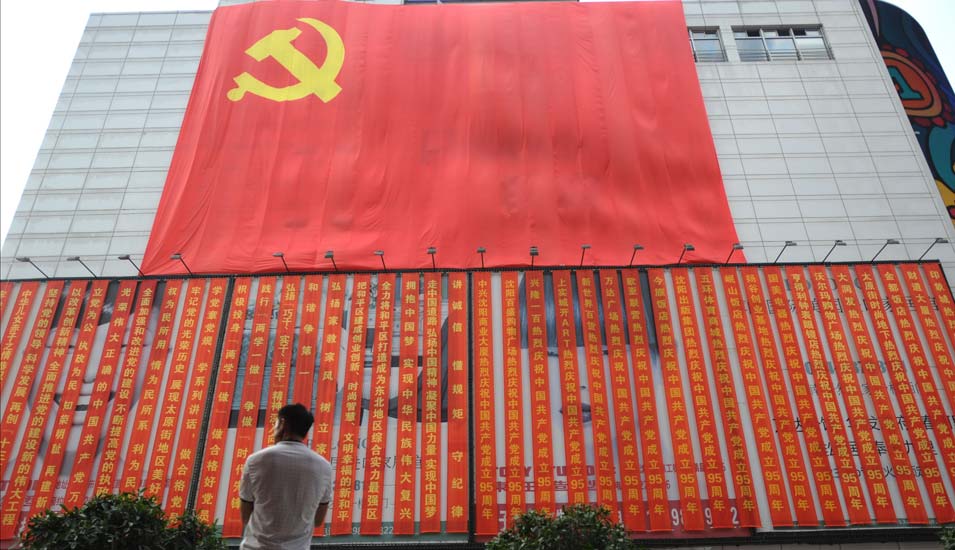 Ein Mann betrachtet die Flagge der Kommunistischen Partei Chinas.