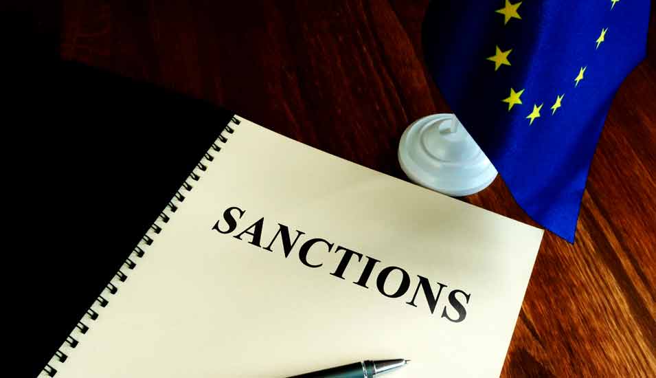 Liste mit Sanktionen und kleine EU-Flagge auf einem Schreibtisch