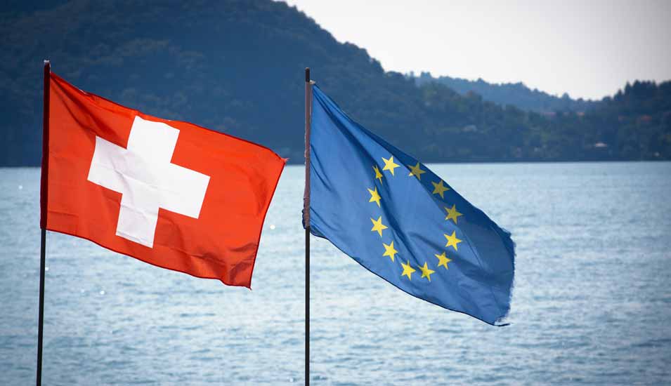 Schweizer Flagge und Europa-Flagge vor einem See