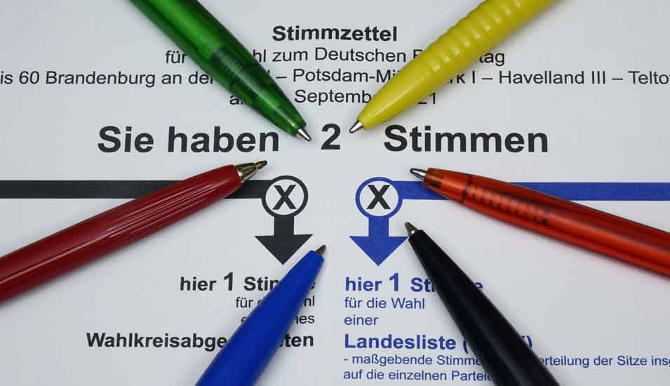 Auf dem Stimmzettel zur Bundestagswahl 2021 liegen Kugelschreiber in den Parteifarben der sechs größten Parteien.