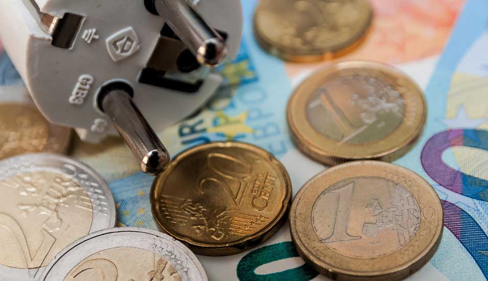 Symbolbild Energiekosten: Euroscheine und -münzen und Stecker eines Elektrogeräts