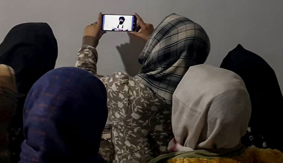 Verschleierte afghanische Frauen in Kabul schauen die Rede des Taliban-Ministers für Höhere Bildung, Neda Mohammed Nadim, auf einem Smartphone.