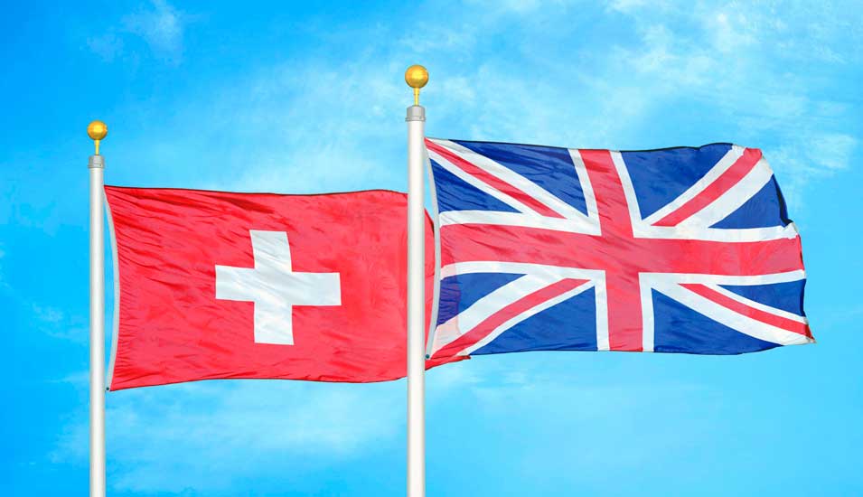 Flaggen der Schweiz und Großbritanniens vor blauem Himmel.