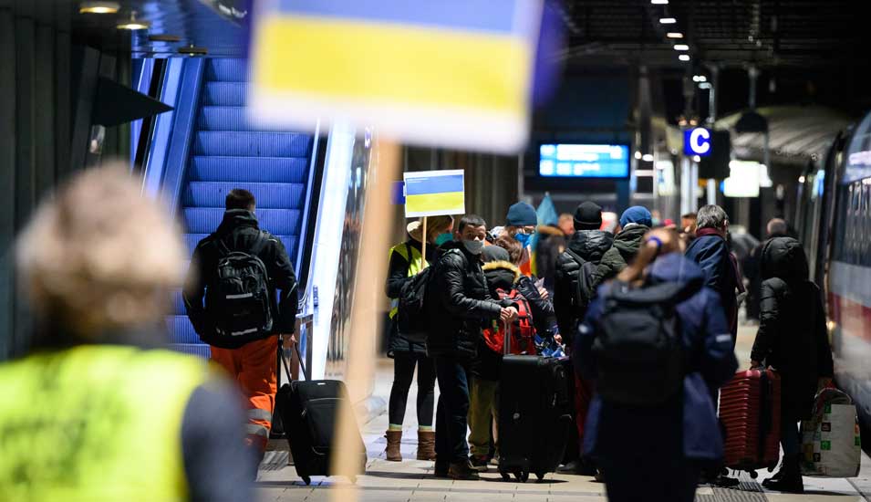 Geflüchtete Ukrainerinner und Ukrainer kommen am Berliner Hauptbahnhof an. Freiwillige halten zur Orietierung Schilder mit der ukrainischen Landesflagge hoch.