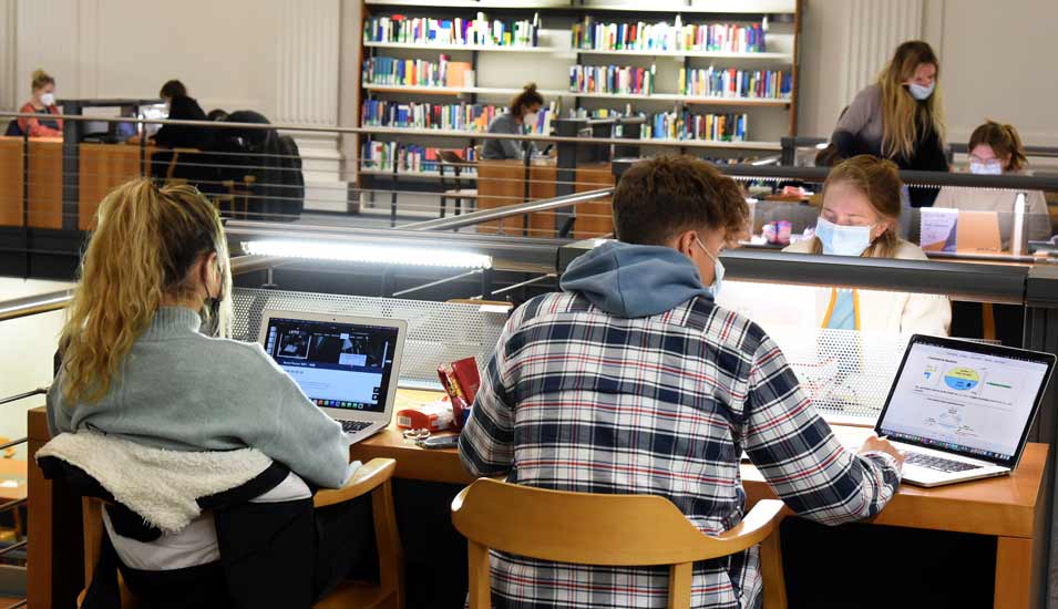 In der Universitätsbibliothek der Uni Leipzig sitzen Studierende an mit Computern bestückten Tischen und lernen eigenständig.
