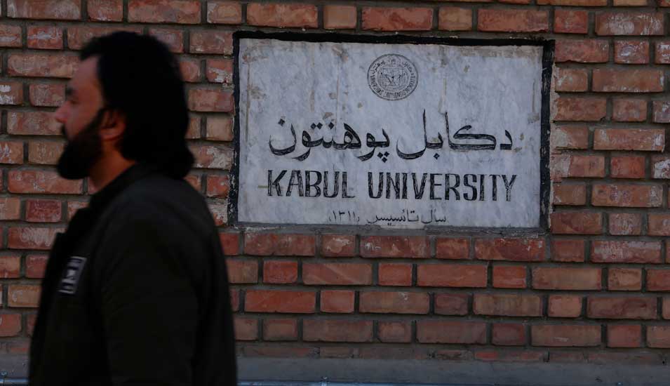 Ein Mann vor einem Schild der Kabul University.