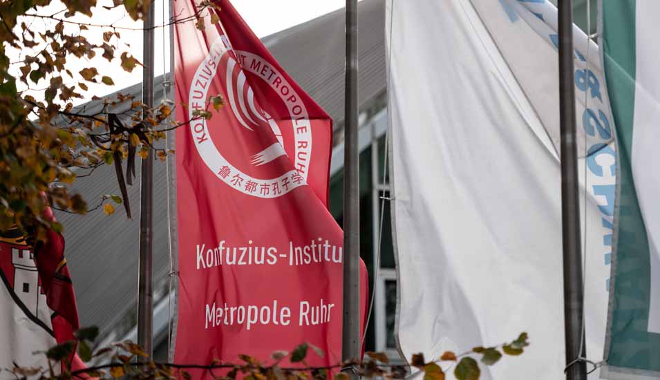 Auf eine Fahne vor dem Tectrum in Duisburg weht das Logo des Konfuzius-Institut Metropole Ruhr.