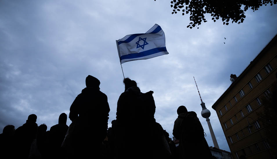 Zwei Menschen halten eine Israel-Flagge in Berlin in die Höhe.