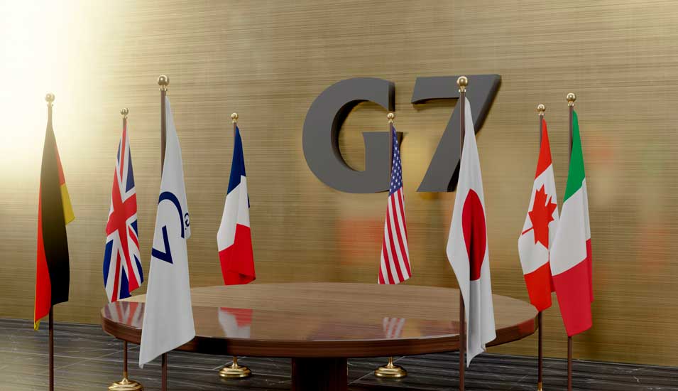 Tisch mit Fahnen der G7-Staaten.