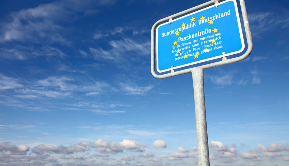 Ein Schild der Bundesrepublik Deutschland, das vor blauem Himmel auf die Passkontrolle hinweist. 