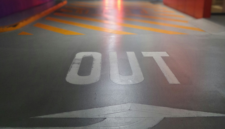 Ein Pfeil auf einem Asphaltboden zeit in Richtung des Wortes "out". 