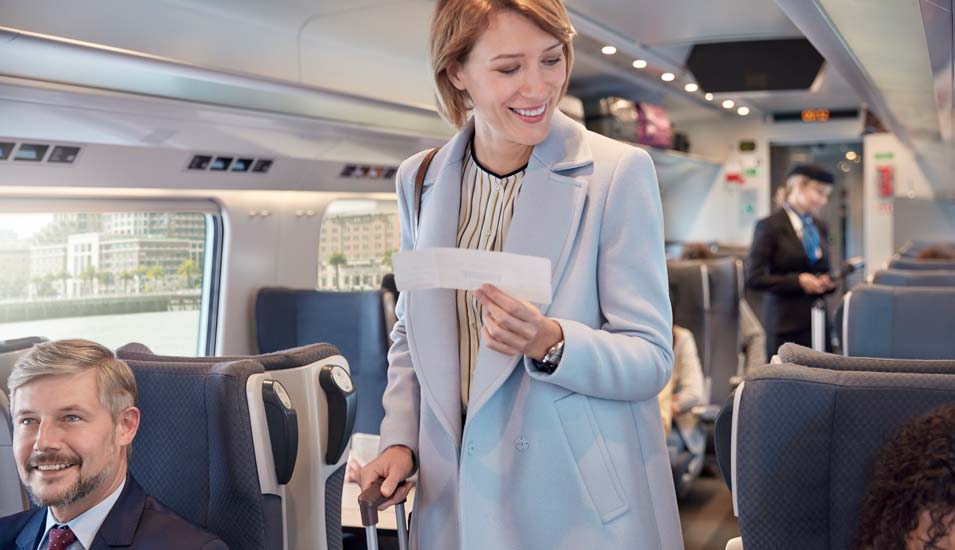 Frau im Zug mit Ticket und Koffer in der Hand