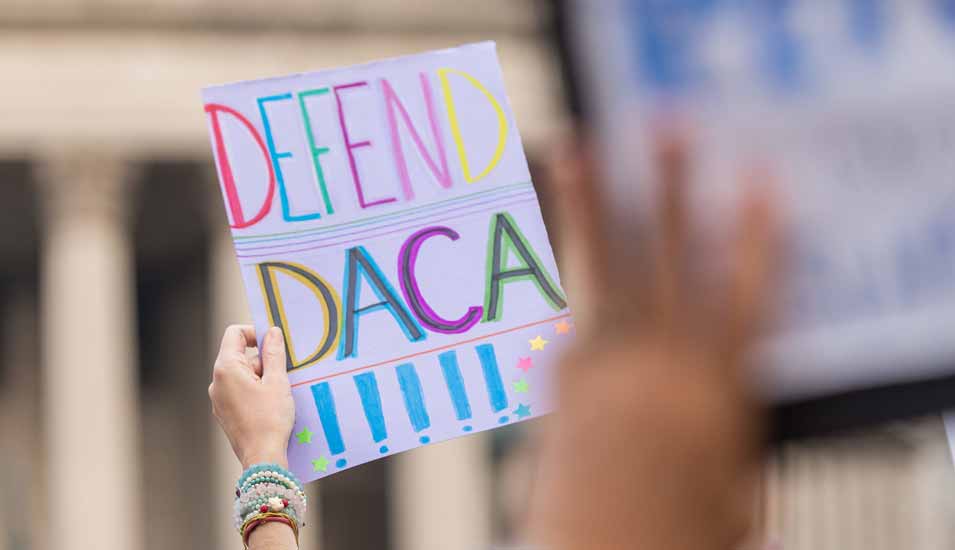 Hand hält Protestplakat mit der Aufschrift "Defend DACA"