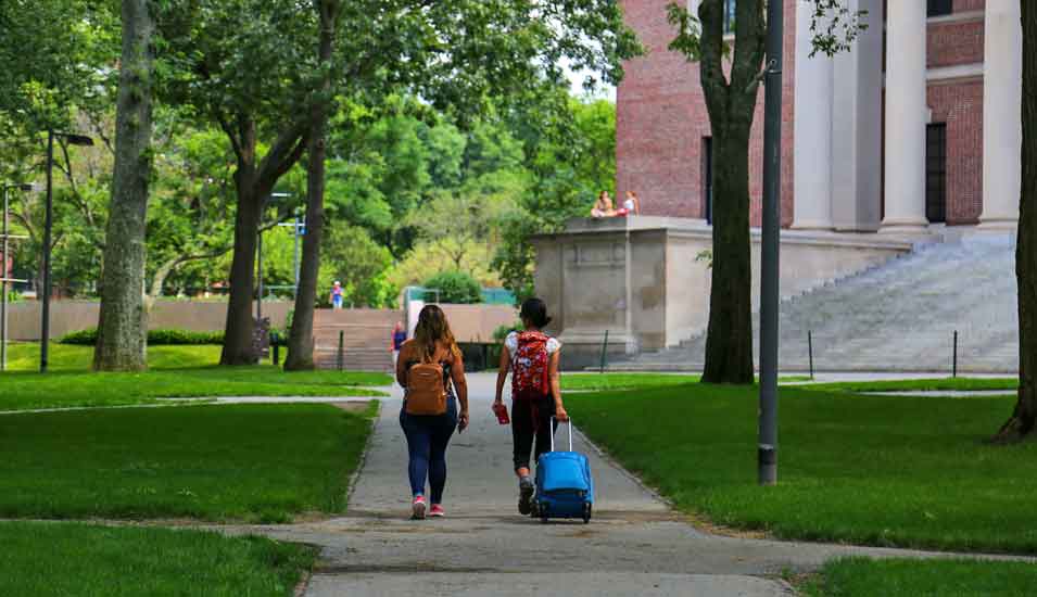 Zwei Studierende mit Koffern auf dem Campus der Harvard Universität