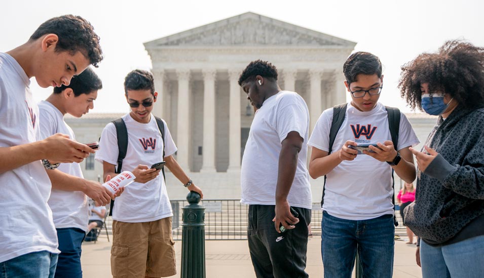 Studierende der Washington Adventist University stehen vor dem Supreme Court in Washington und lesen dessen Urteil zu "affirmative action" an US-Universitäten auf ihren Smartphones.