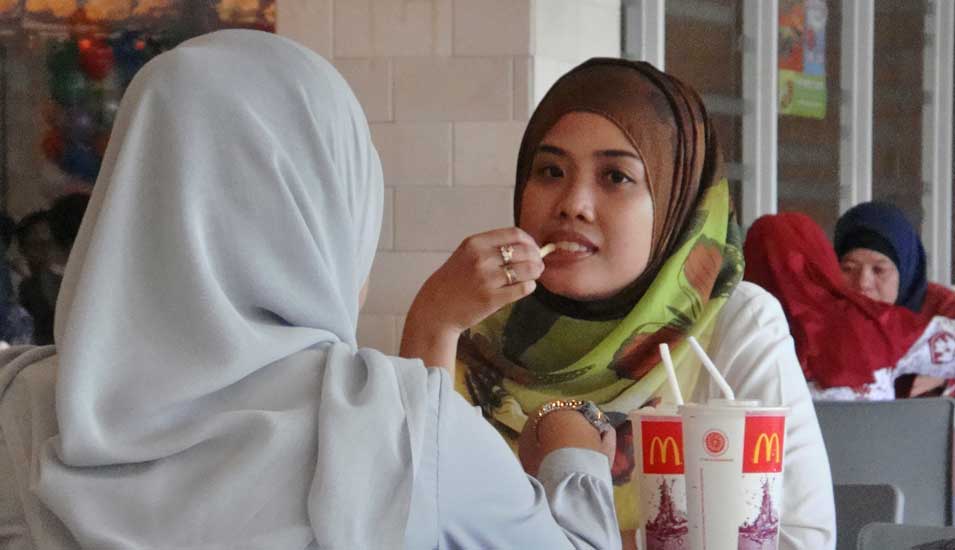 Islamisch gekleidete Frauen essen in Schnellimbiss