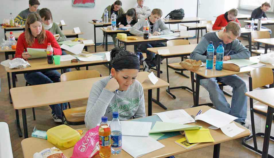 Das Foto zeigt mehrere Schüler an Tischen bei der Abiturprüfung.