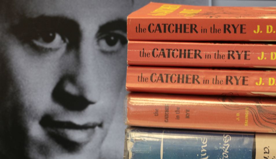 Das Bild zeigt ein Porträtfoto von J. D. Salinger mit einigen Exemplaren von "The Catcher in the Rye"