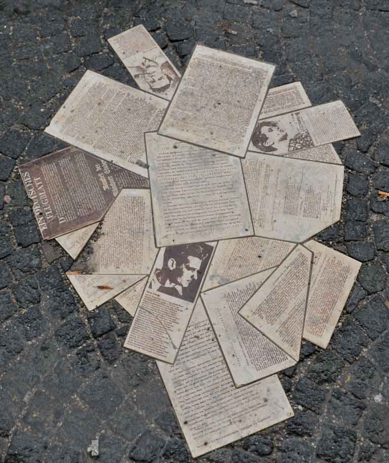 Das Foto zeigt ein Denkmal für die Weiße Rose mit verstreuten Flugblättern