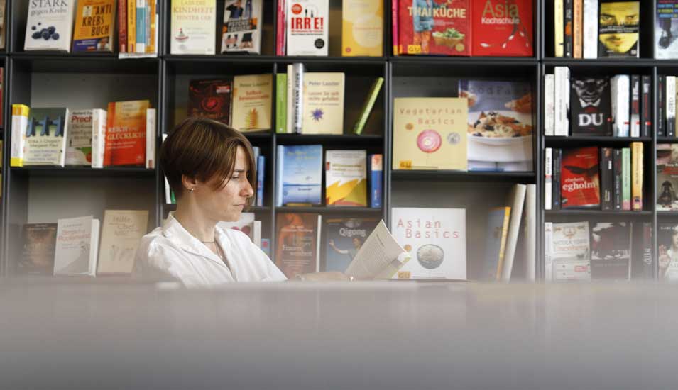 Das Foto zeigt eine lesende Frau in einer Buchhandlung