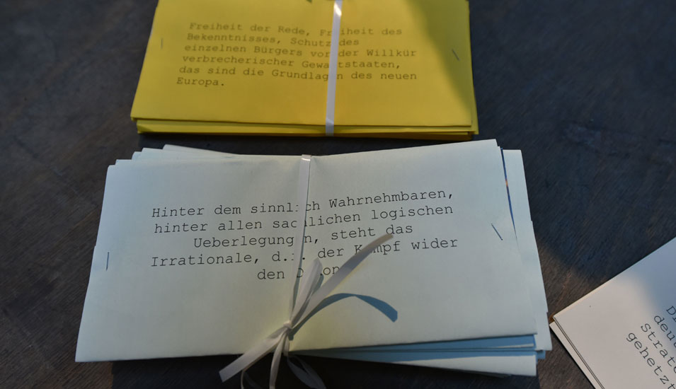 Das Foto zeigt Zettel mit Zeilen aus den Flugblättern der Weissen Rose.