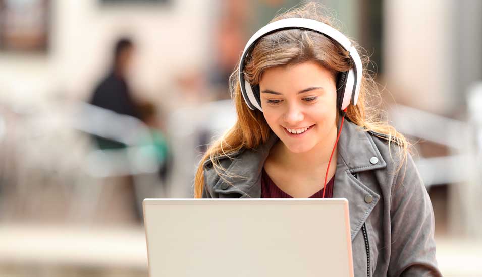 Eine Schülerin sitzt mit Kopfhörern am Laptop
