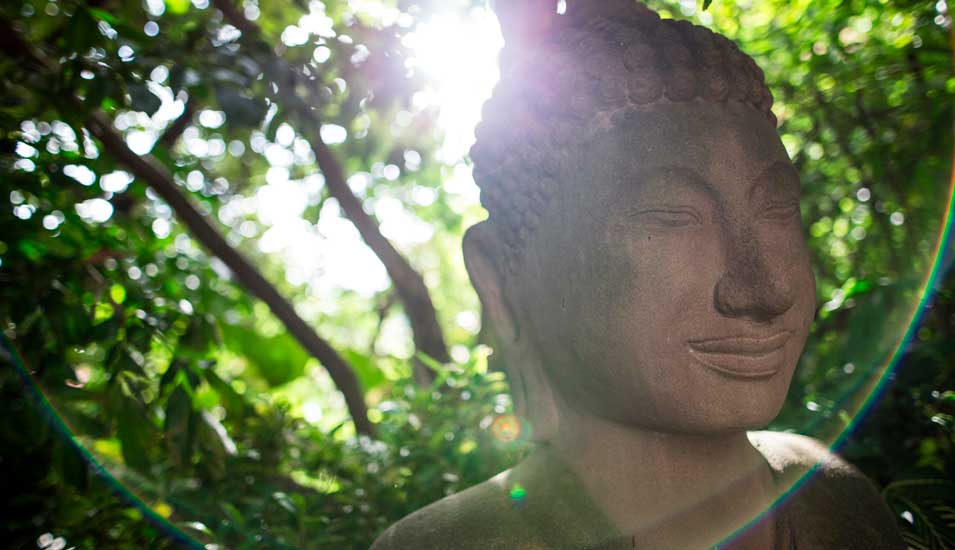 Buddha-Skulptur mit Sonnenlicht von hinten, das einen Heiligenschein erzeugt