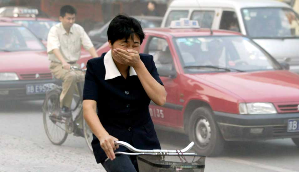 Ein Fahrradfahrer hält sich wegen Smogs die Hand vor den Mund