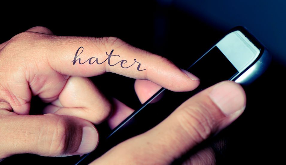 Smartphone in einer Hand, auf einem Finger steht "Hater".